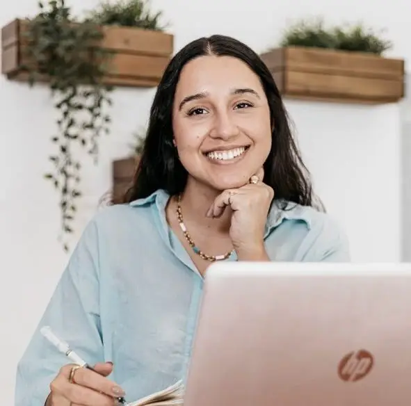 Psicóloga Júlia Garioli sorrindo durante consulta de psicologia online em ambiente acolhedor